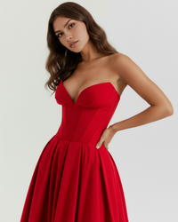 Robe rouge bustier ajusté, corset et jupe évasée plissée.