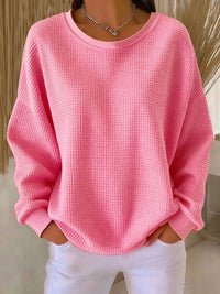 Sweat minimaliste rose clair en tissu texturé, encolure ronde, manches longues amples.