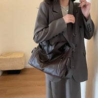 Sac cabas en cuir foncé, bandoulière ajustable, deux poches zippées sur le devant