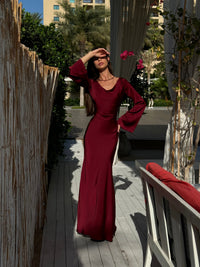 Robe longue bordeaux à manches évasées, encolure ronde et taille marquée.