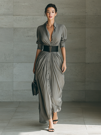 Robe longue grise plissée, boutons devant, manches 3/4, taille ceinturée.