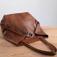 Grand sac cabas rétro marron, drapé sur le côté, poignée courte et anneau métallique.