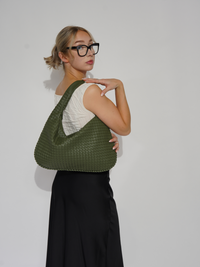Sac d’épaule Samara tressé vert sauge, porté sur l’épaule avec anses longues.