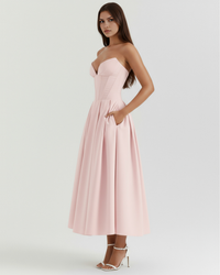 Robe rose poudré sans manches, décolleté cœur et jupe évasée mi-longue avec plis.
