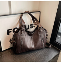 Sac cabas en cuir brun, anses courtes et bandoulière, poches zippées sur le devant