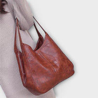 Sac vintage en cuir brun avec anses longues, coutures décoratives et poche plaquée