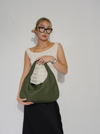 Sac d’épaule Samara tressé vert sauge, porté devant, grande ouverture et doublure visible.