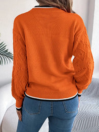 Pull en tricot orange à texture ajourée, col rond côtelé et poignets avec rayures blanches