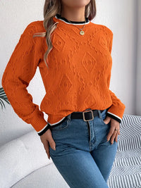 Pull en tricot orange à motifs texturés, col rond avec bande rayée blanc/noir et boutons