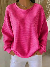 Sweat minimaliste rose fuchsia en tissu texturé, encolure ronde, manches longues amples.