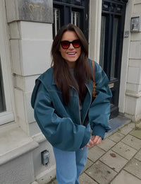 Veste en cuir oversize bleue/vert foncé, fermeture zippée et surpiqûres blanches.