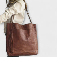 Sac à main marron foncé avec poche avant et anses longues.