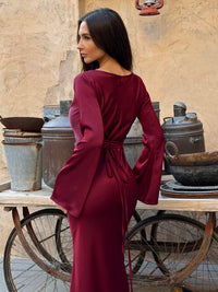 Robe longue bordeaux dos avec ceinture nouée à la taille et manches longues évasées.