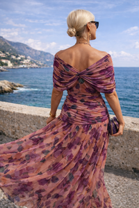 Robe longue violette à dos nu noué, motif floral, épaules dénudées.
