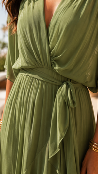 Robe verte cache-cœur avec taille nouée et drapé plissé, manches courtes.