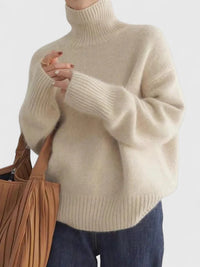 Pull à col montant beige, col et poignets côtelés, coupe ample.