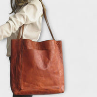 Sac à main marron avec poche frontale et anses longues, style cabas.