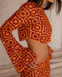 Haut court orange à motifs géométriques circulaires, manches longues évasées, dos partiel