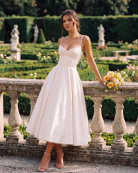Robe ivoire à bretelles fines et jupe évasée, corsage avec dentelle, bouquet en main