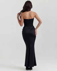 Robe longue noire au dos nu avec coutures verticales et jupe évasée.