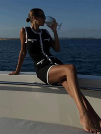 Robe courte sans manches noire à liseré blanc, coupe évasée et boutons décoratifs