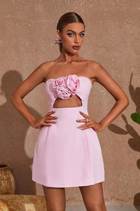 Robe courte rose pâle sans bretelles, fleur rose en relief au niveau du buste