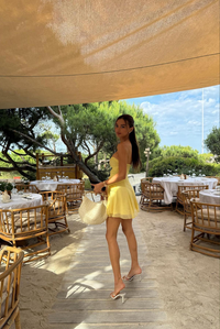 Robe courte jaune à buste noué et anneaux dorés, jupe légère et manches volant