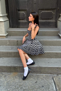 Robe courte sans manches en maille noire à motif géométrique, évasée, dos vu de côté.