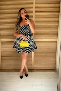 Robe courte sans manches en maille noire à motif en losanges, encolure carrée, volume évasé.