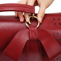 Main tenant la bandoulière du sac à main cartable en cuir rouge