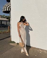 Robe longue satin crème dos nu, coupe élégante et fleur appliquée au buste