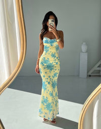 Robe longue ajustée jaune clair à motif floral bleu, bretelles fines, décolleté étroit.