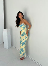 Robe longue jaune clair à motif floral bleu, bretelles fines, coupe près du corps.