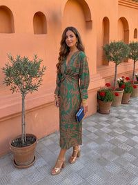 Robe midi imprimée verte, manches longues, décolleté et ceinture noués à la taille.