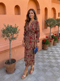 Robe midi imprimée rouge, manches longues, décolleté noué et ceinture ajustable.