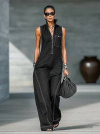 Combinaison minimaliste noire sans manches, zip devant, poches, surpiqûres contrastées.
