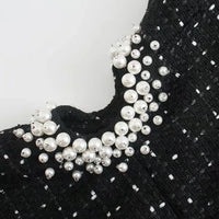 Détail des perles blanches en appliqué sur tissu noir texturé