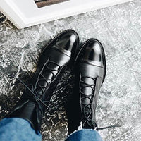 Bottes en cuir noir à lacets, bouts pointus, vue de dessus sur sol.