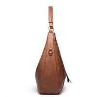 Sac à bandoulière classique en cuir marron, porté sur l’épaule, design évasé