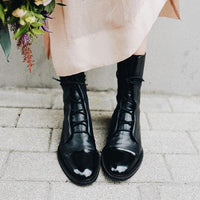Bottes en cuir noir à lacets, vue de face, bouts pointus, semelles contrastées.