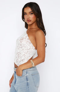 Top d’été à nouer en dentelle blanche, coupe asymétrique avec nœud sur le côté.