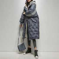 Doudoune longue bleue matelassée, capuche à bord beige, fermeture zippée