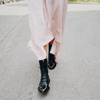 Bottes noires à lacets avec bout pointu, portées avec pantalon clair.