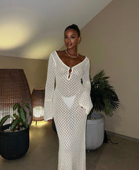 Robe longue blanche en maille ajourée, encolure V avec patte, manches longues évasées.