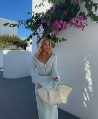 Robe longue bleue en maille ajourée, décolleté V à patte, manches longues évasées.