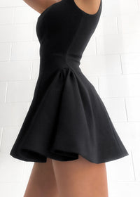 Robe courte noire évasée, sans manches, détail de pli au niveau de la taille