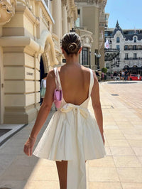 Mini-robe blanche dos ouvert, jupe évasée froncée et nœud à la taille dans le dos