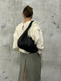 Sac d’épaule tressé noir porté à l’épaule, silhouette hobo