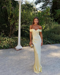 Robe longue en satin jaune, encolure bateau, buste drapé et jupe près du corps