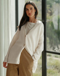 Gilet cocon en maille ivoire, col V boutonné, manches longues et forme ample.